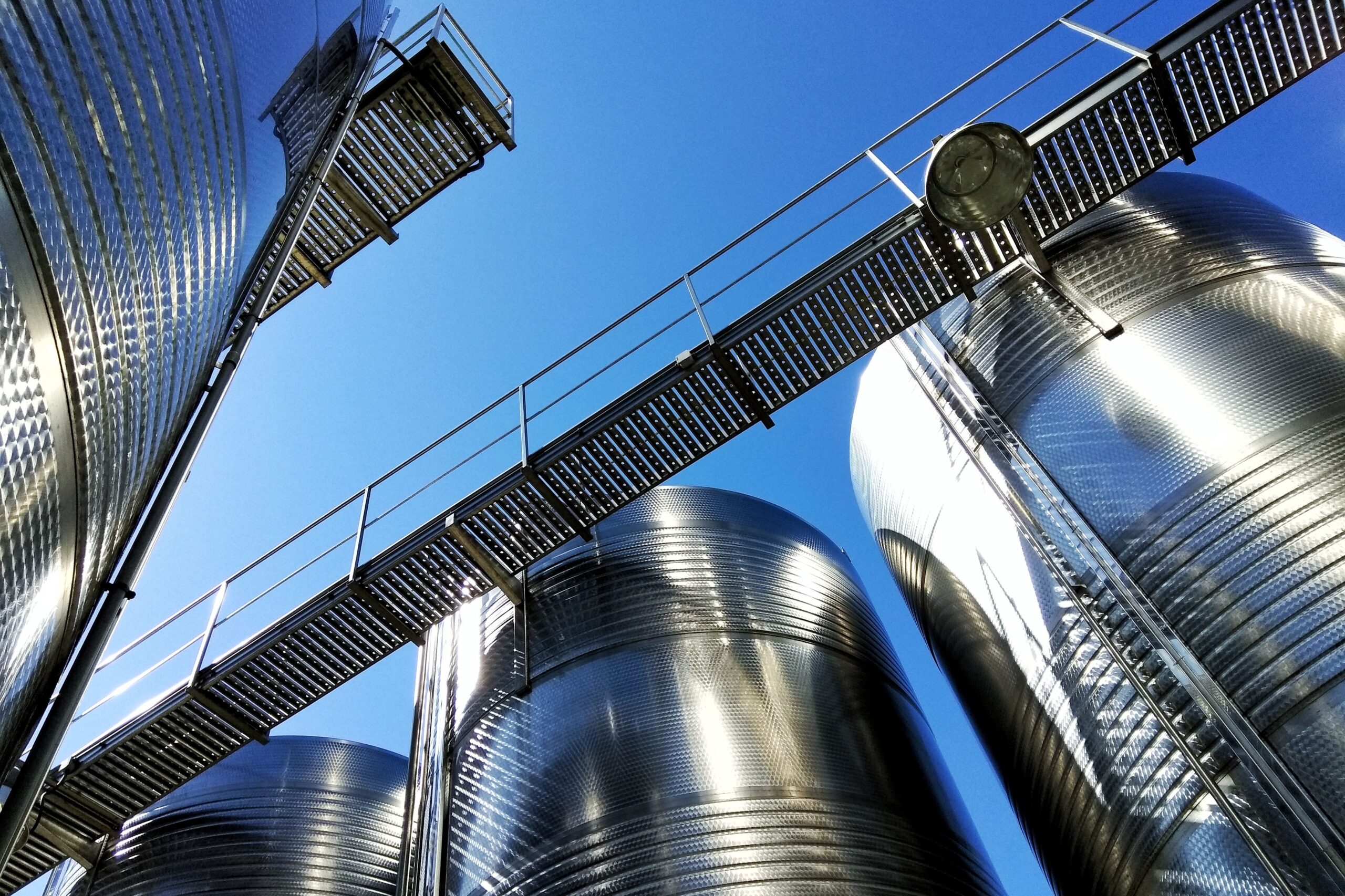 A low angle shot of huge stainless steel tanks in an industrial center